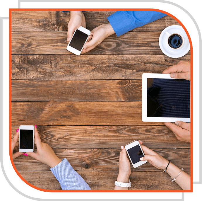 A group of people sitting around a table with cell phones.