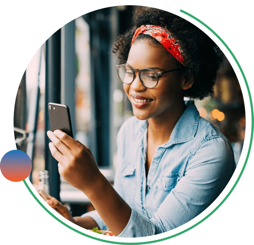 A woman sitting at a table looking at her phone.